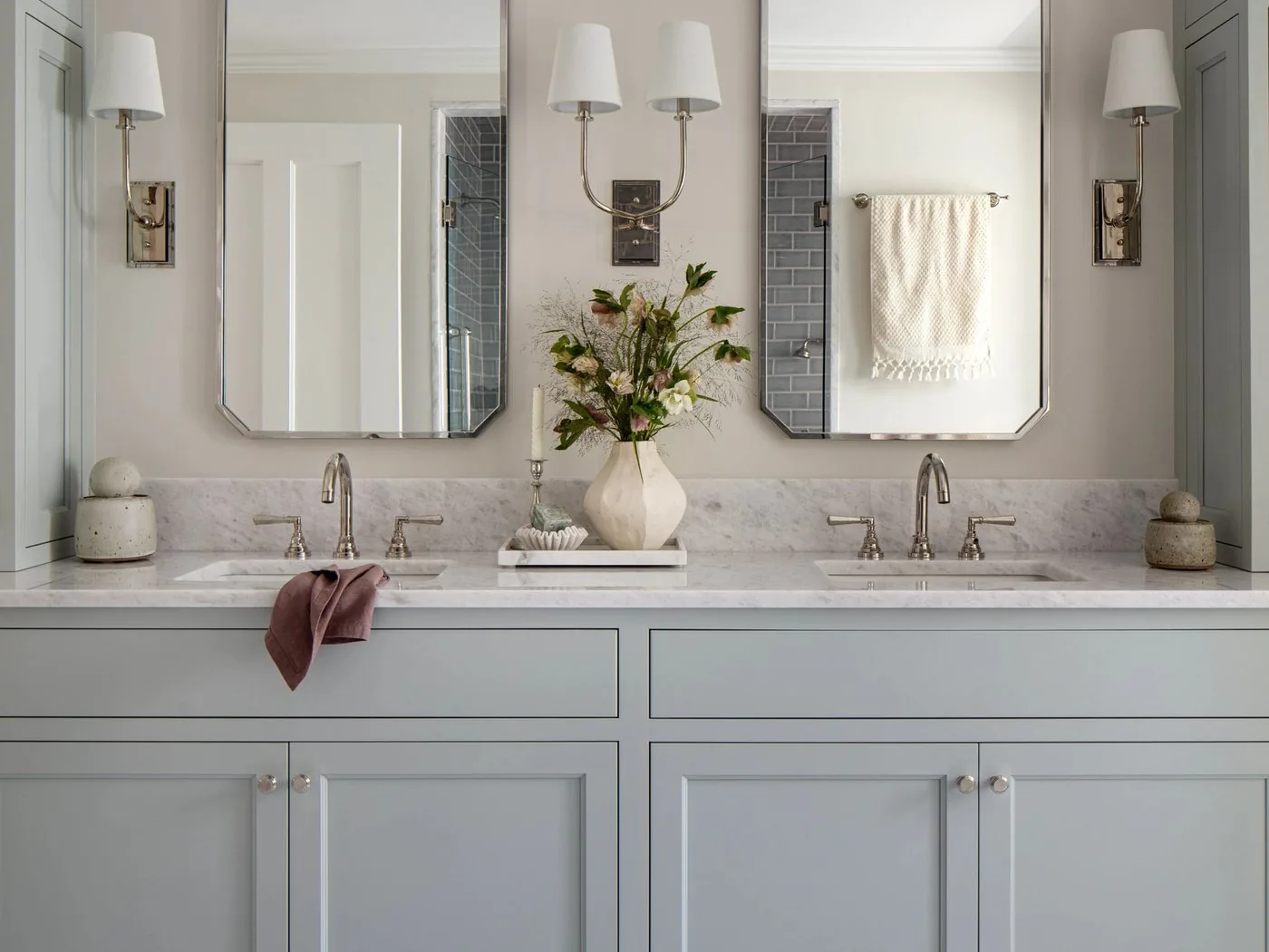 A double vanity in a bathroom with a stone top and framed mirrors