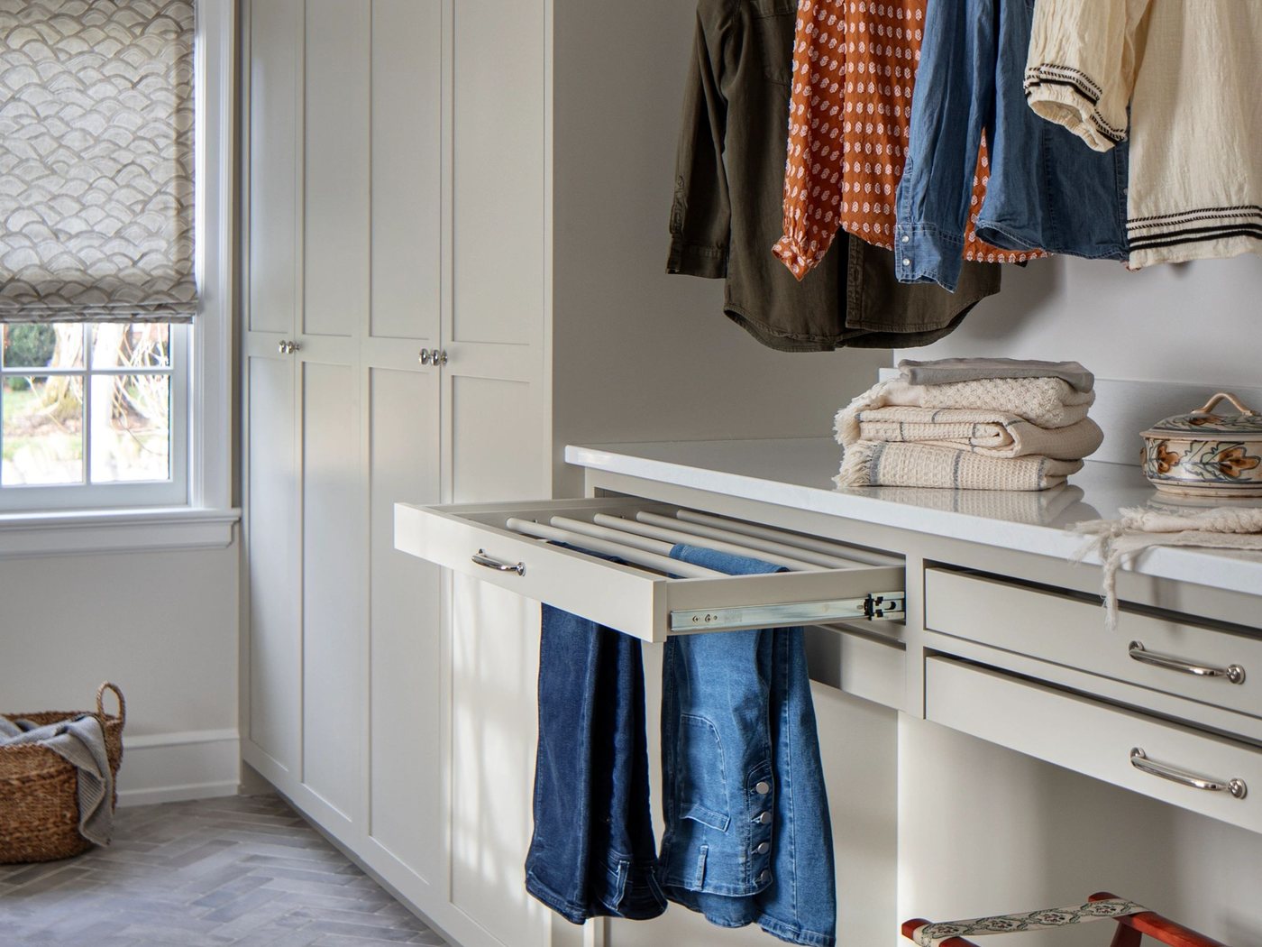 A fitted closet with hanging rails, drawers and a pull out rack