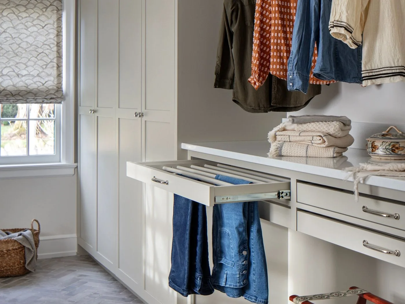 A fitted closet with hanging rails, drawers and a pull out rack