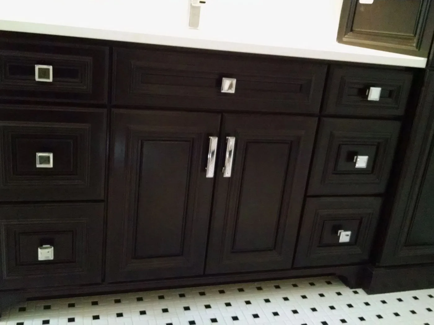 A dark stained vanity with square cabinet hardware