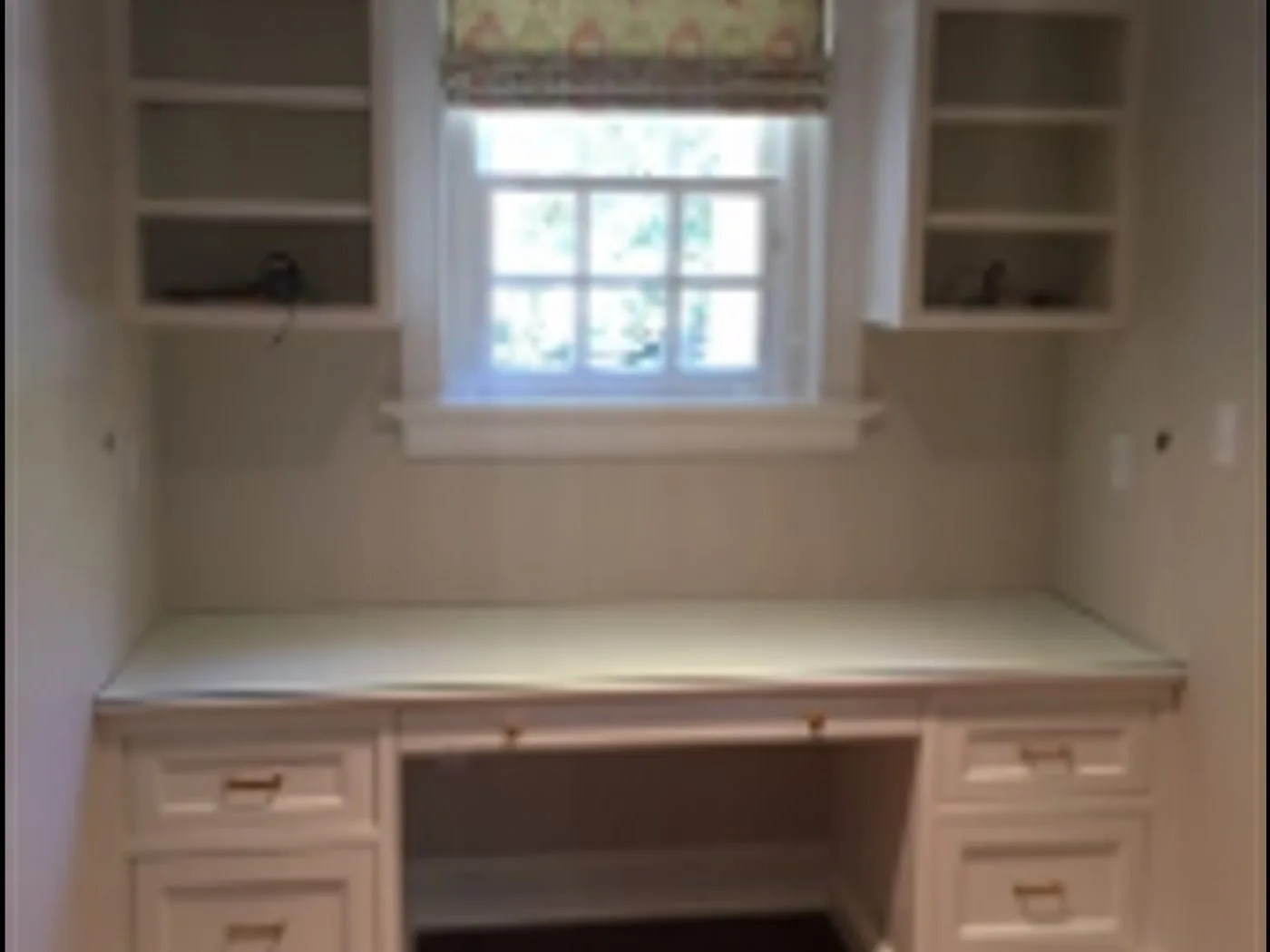 A built-in home office desk with drawers and shelving around a window