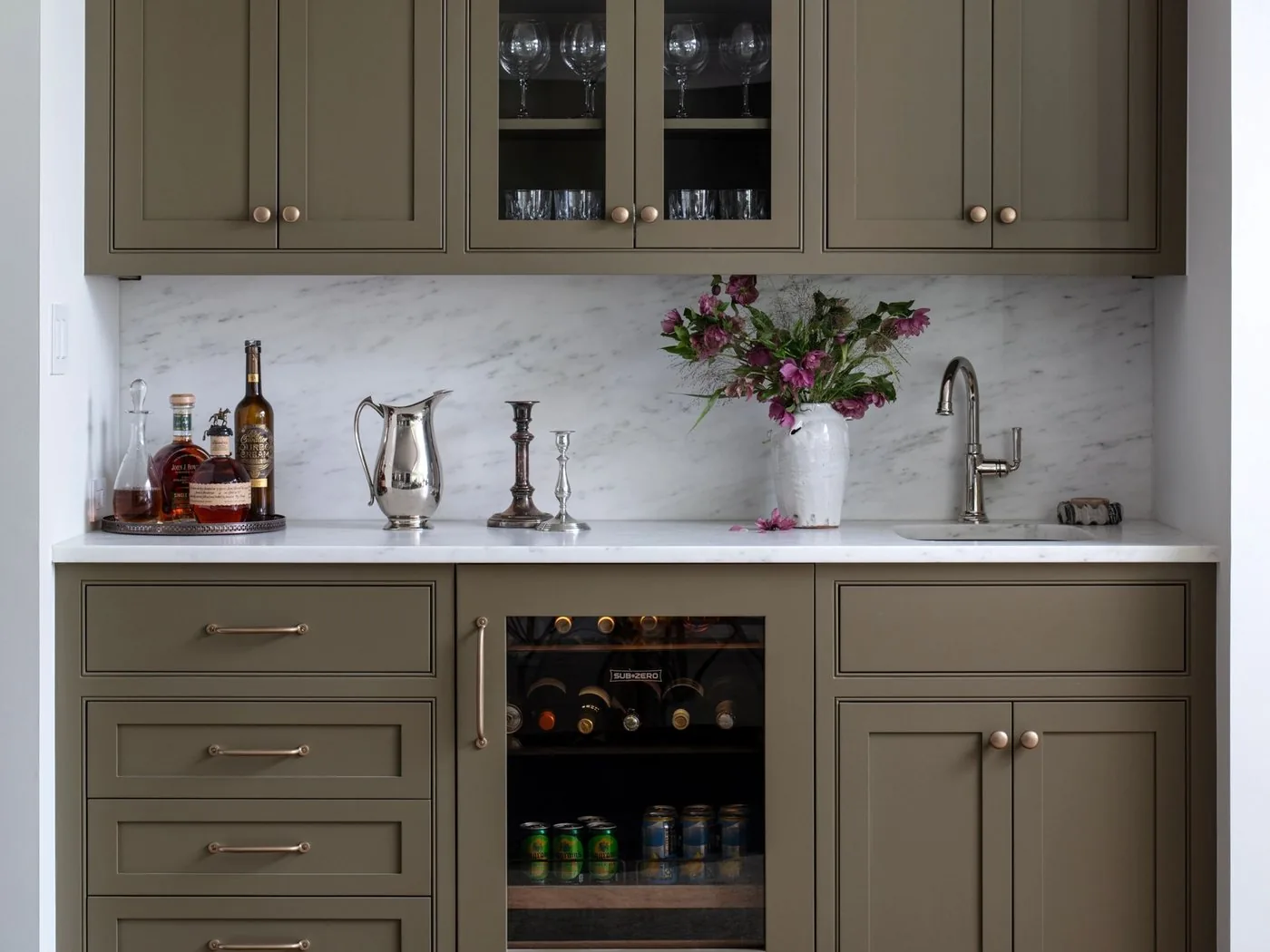 A wet bar with glass front upper cabinets and an under counter cooler